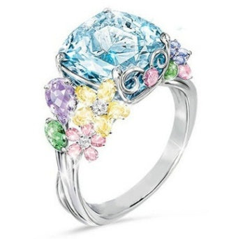Ring with a large blue gemstone and smaller multicolored stones on a white background