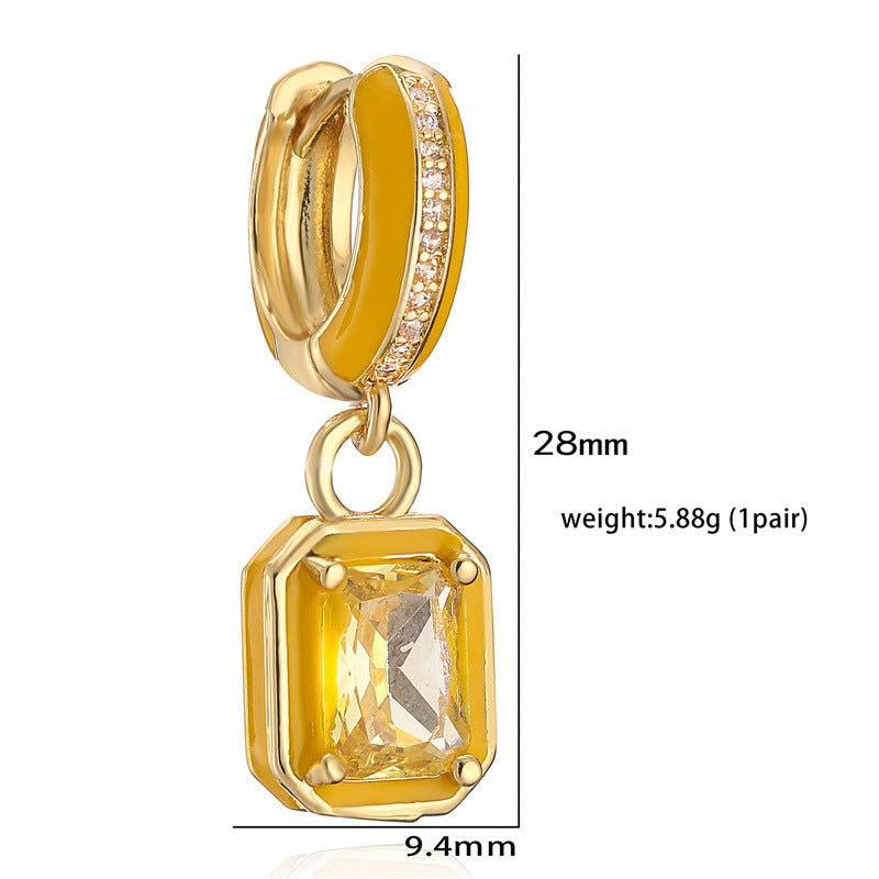 Gold hoop earring with a yellow gemstone pendant on a white background