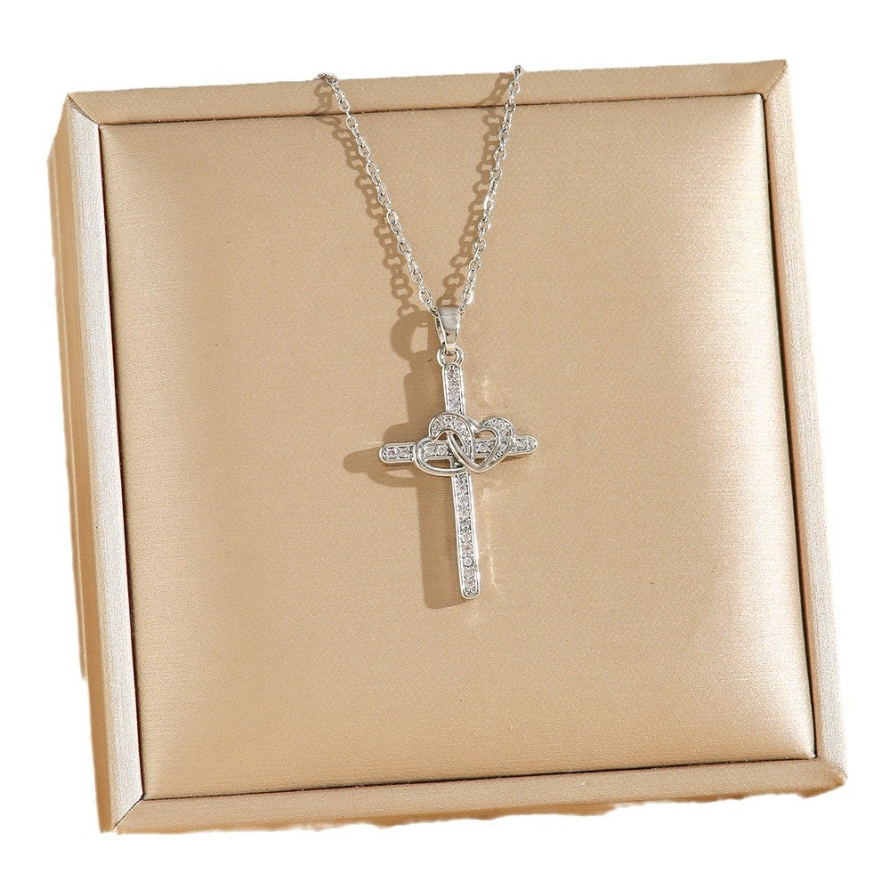 Silver cross necklace with chain on a beige box