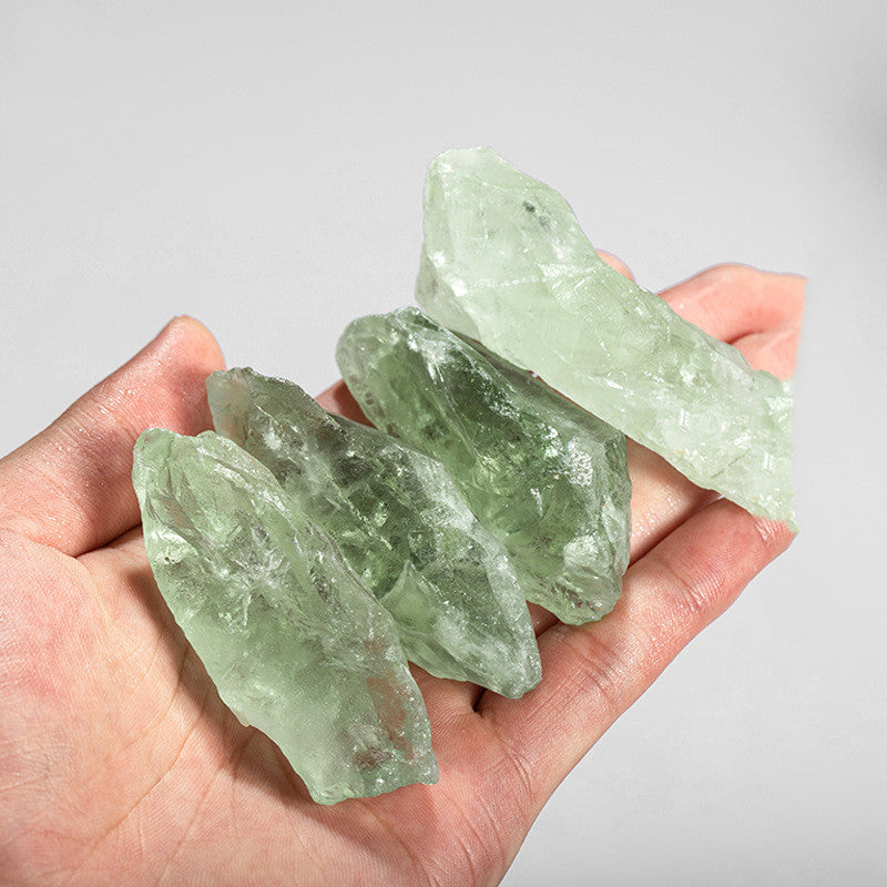 Hand holding three green crystals against a gray background