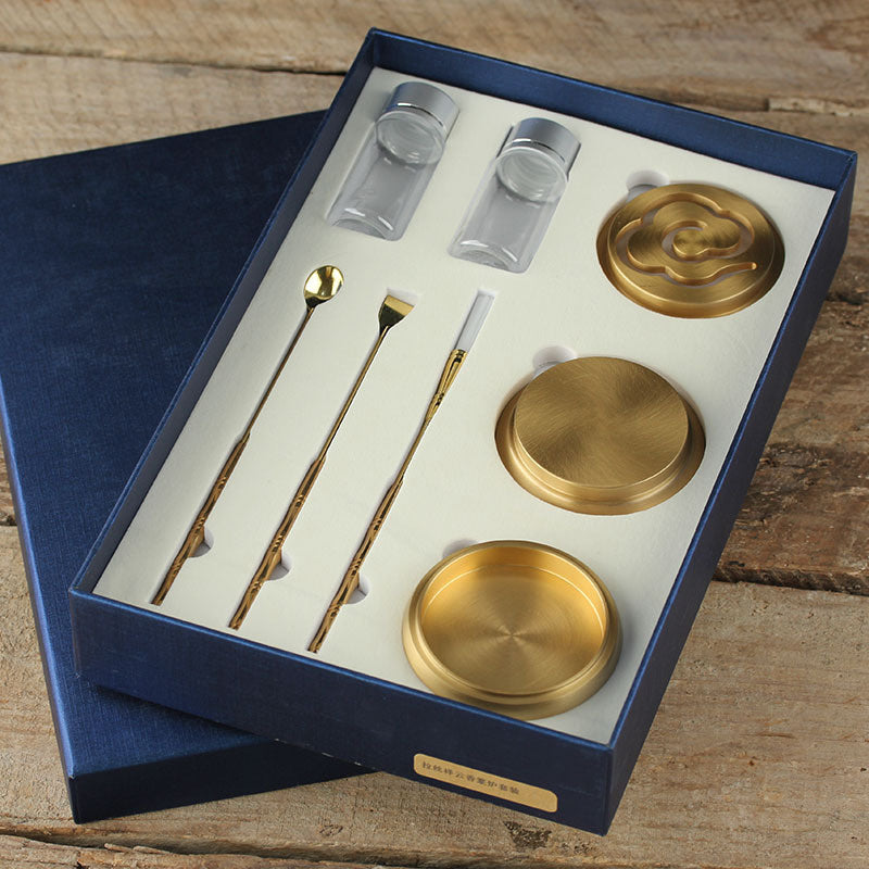 Set of gold drink accessories including straws, stirrers, and coasters in a blue box on a wooden surface.