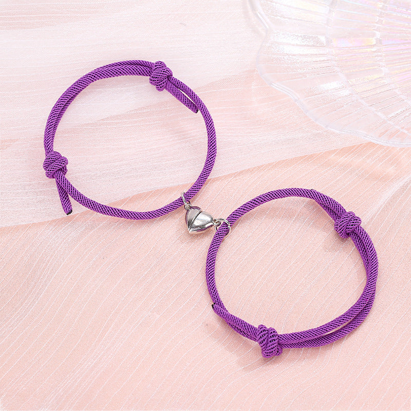 Two purple bracelets with silver heart charms on a pink surface