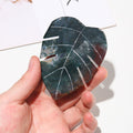 Hand holding a leaf-shaped stone with a white background