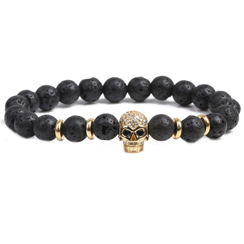 Black beaded bracelet with a gold skull charm on a white background