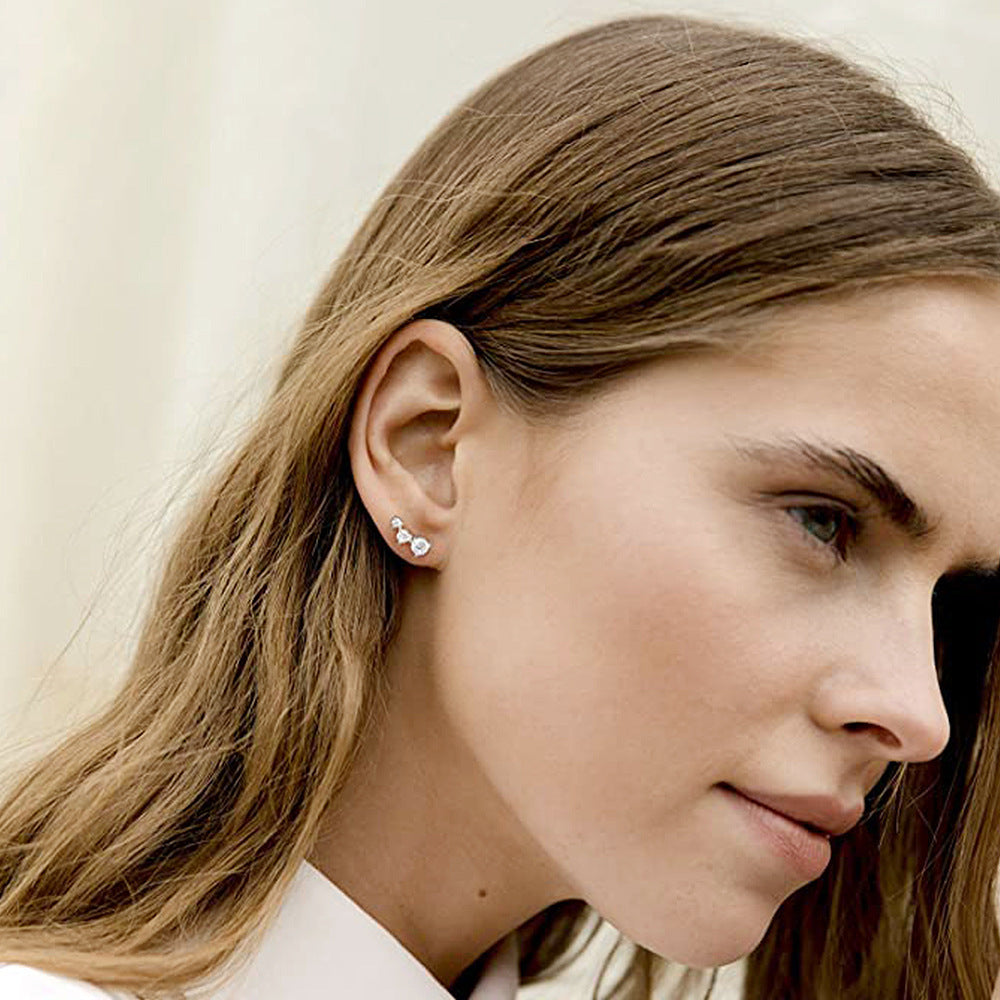 Close-up of a woman wearing earrings with a neutral background
