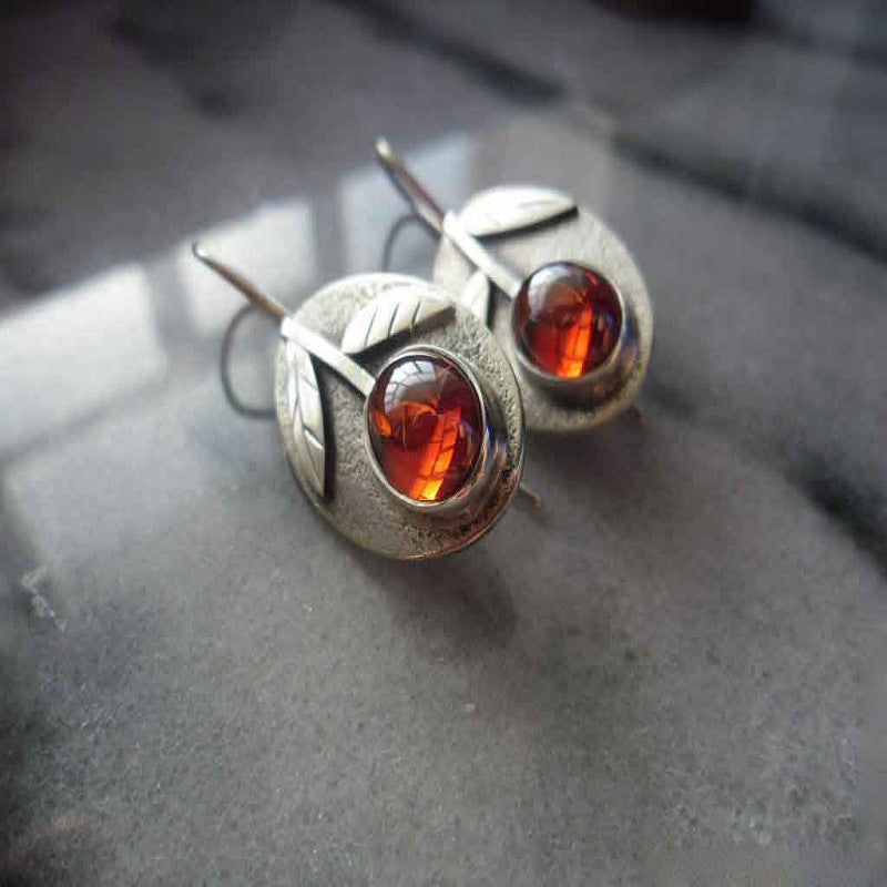 Pair of silver earrings with amber stones on a textured surface