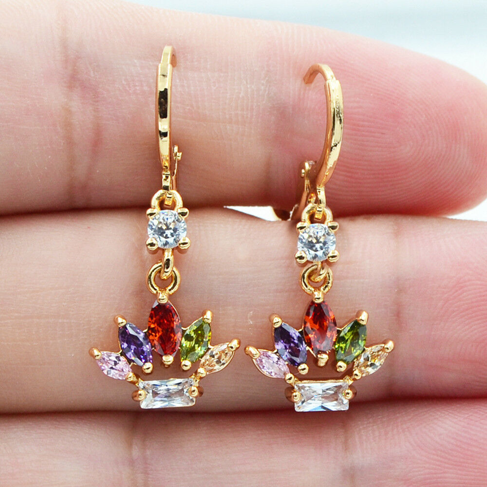 Gold earrings with colorful gemstones held between fingers