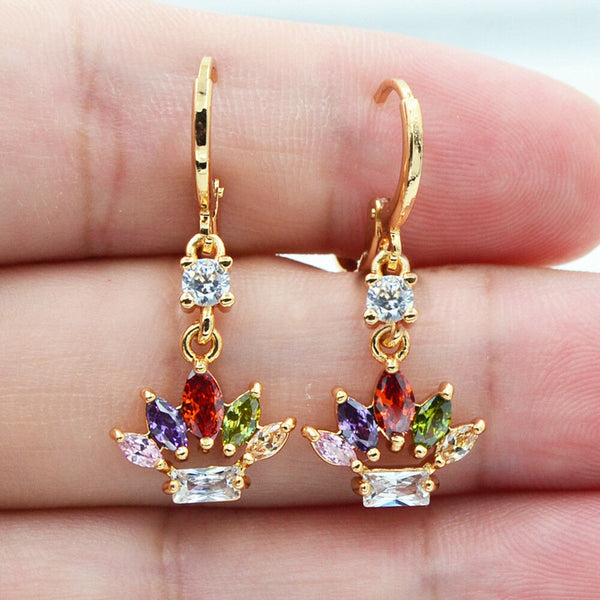Gold earrings with colorful gemstones held between fingers
