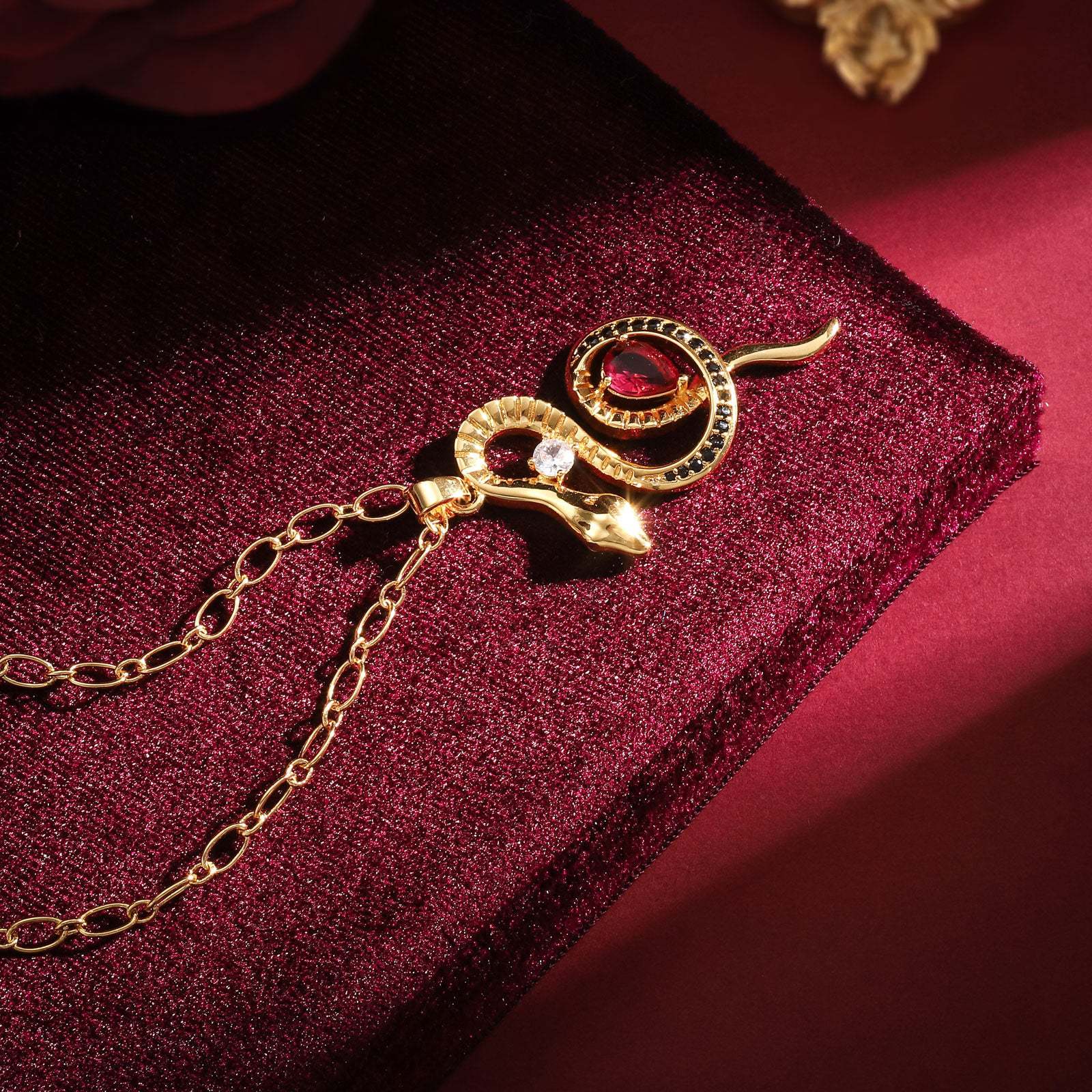 Gold necklace with a red gemstone on a red fabric background