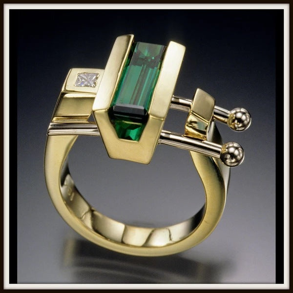 Gold ring with green gemstone and diamond on a dark background