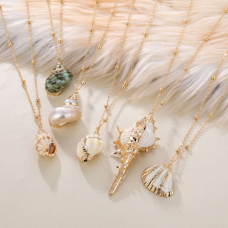 Gold necklaces with shell pendants on a textured surface