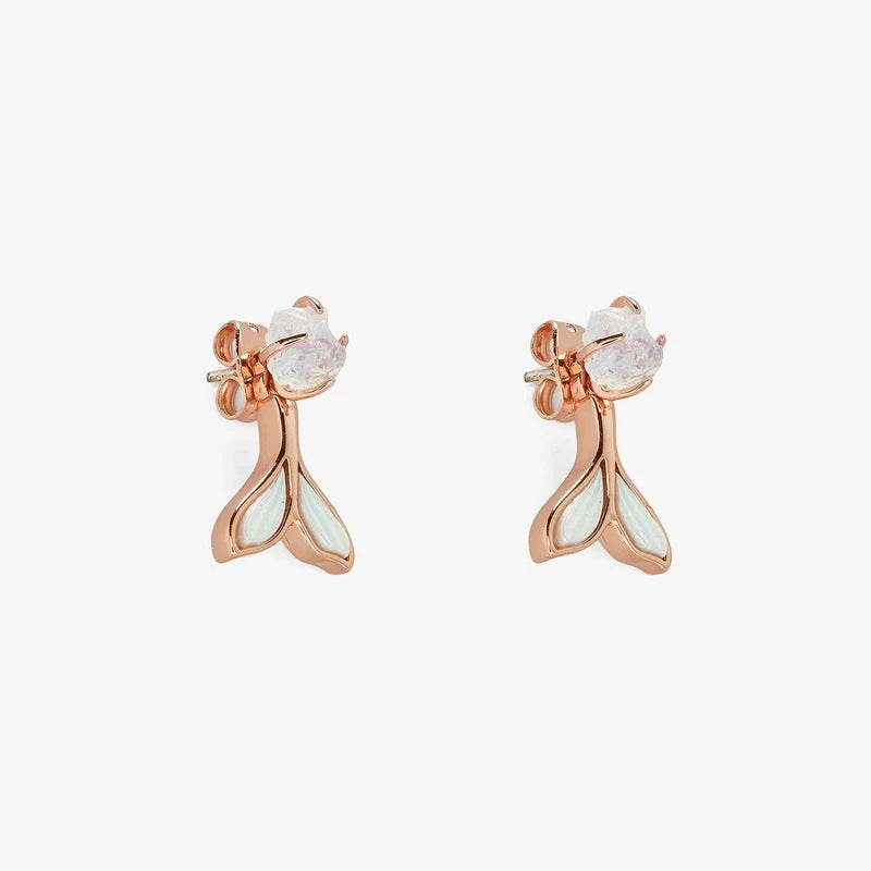 Rose gold earrings with white gemstones on a light beige background