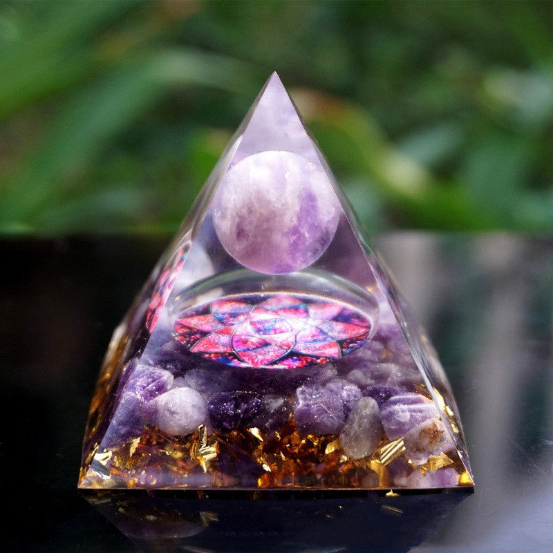 Triangular pyramid with purple stones and a colorful interior against a blurred green background
