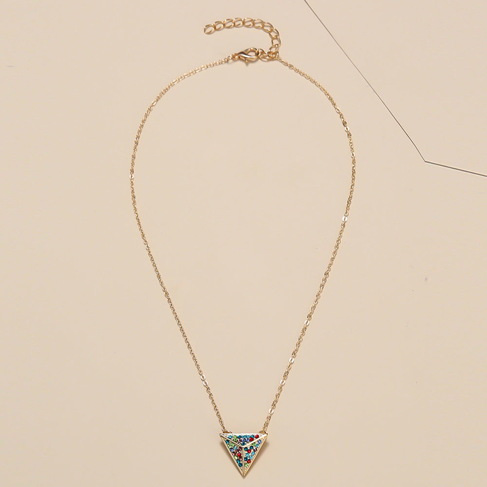 Gold necklace with a colorful triangular pendant on a beige background