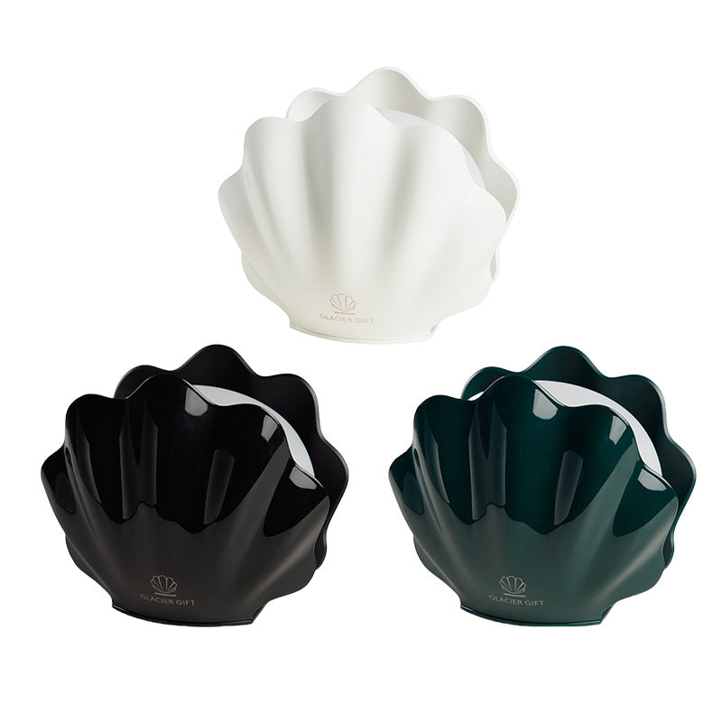 Three shell-shaped bowls in white, black, and green on a white background