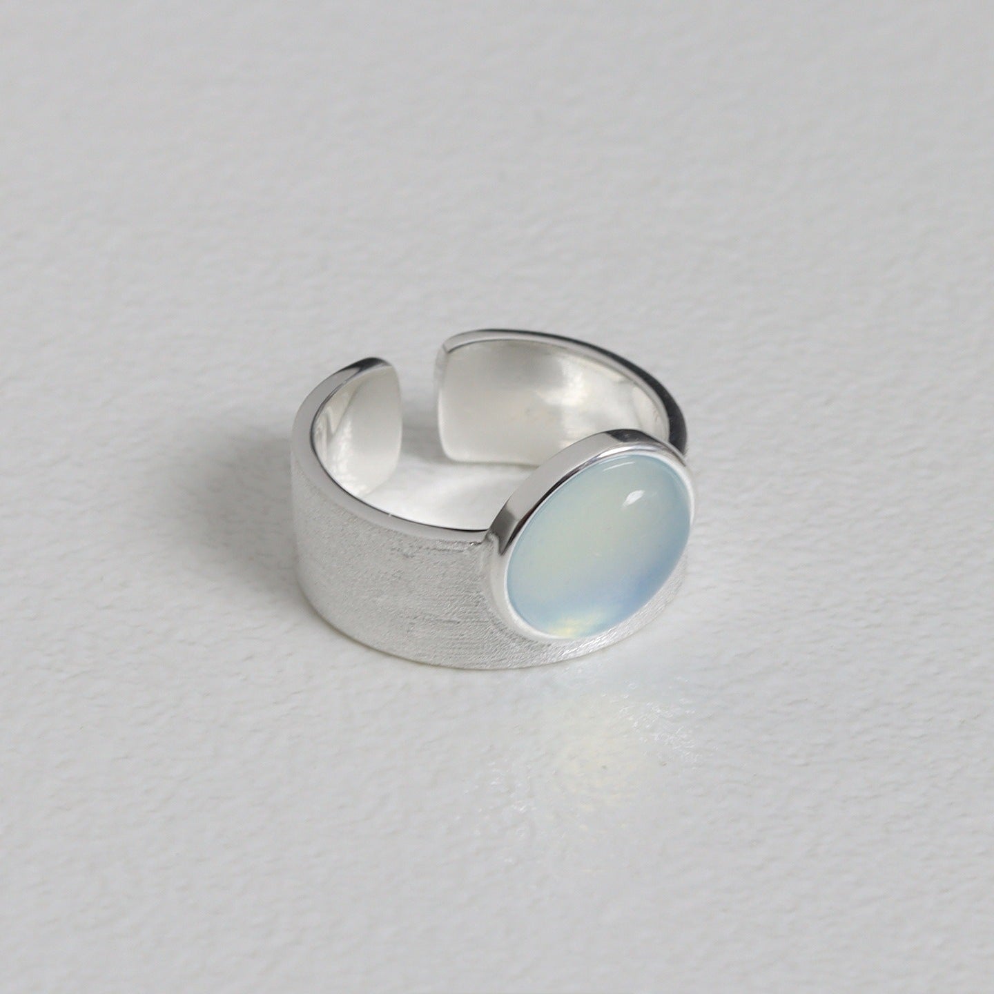 Silver ring with a light blue stone on a gray background