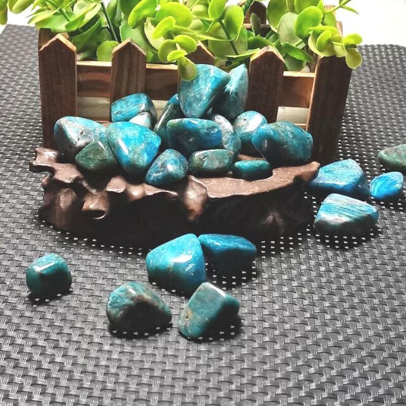Turquoise stones on a textured surface with a wooden planter in the background