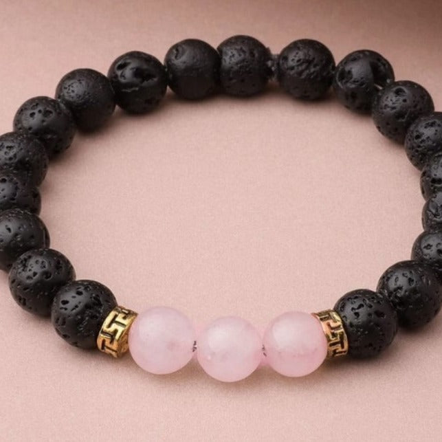 Black lava rock bracelet with pink beads on a pink background