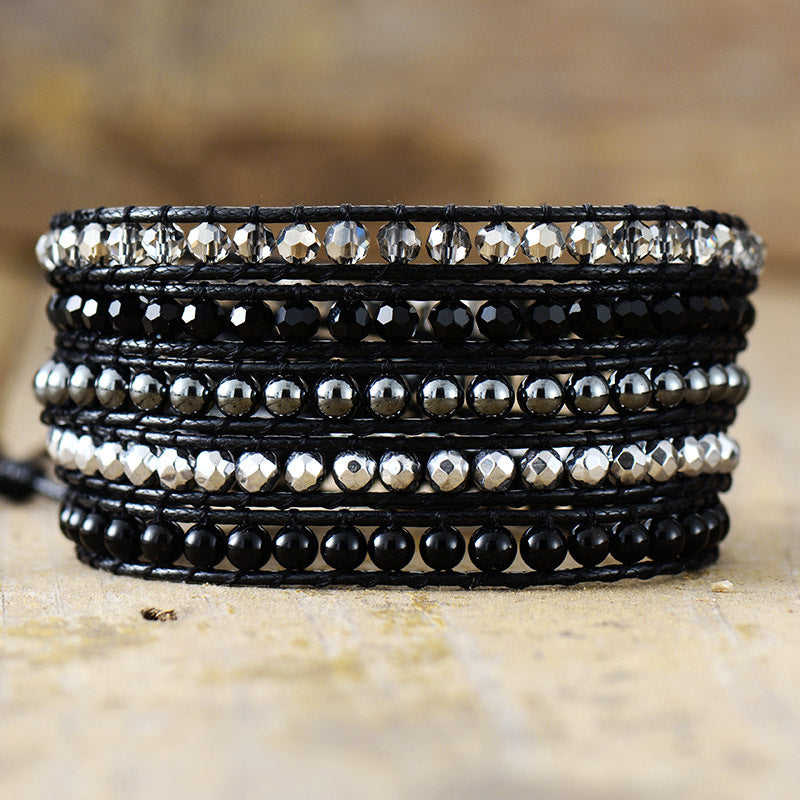 Multi-layered bracelet with black beads and silver accents on a textured surface