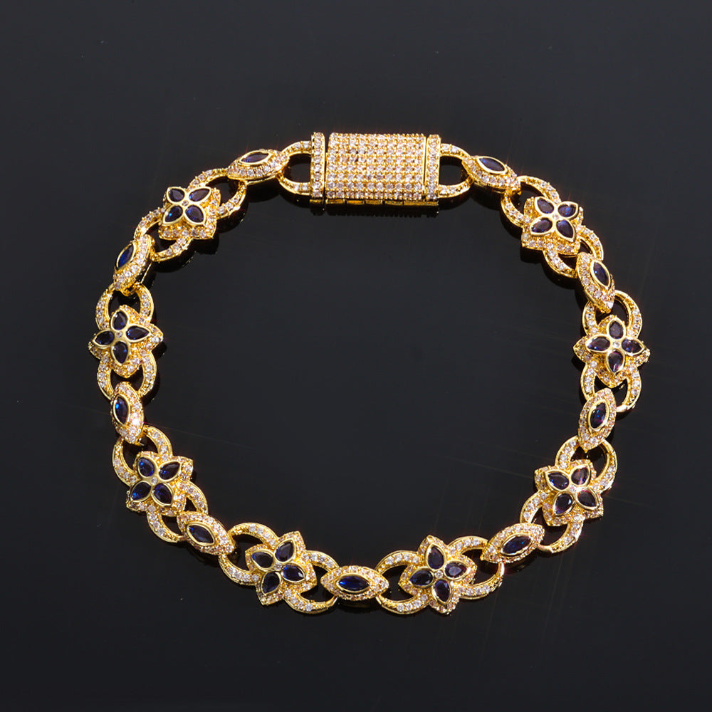Gold bracelet with floral designs and blue stones on a black background
