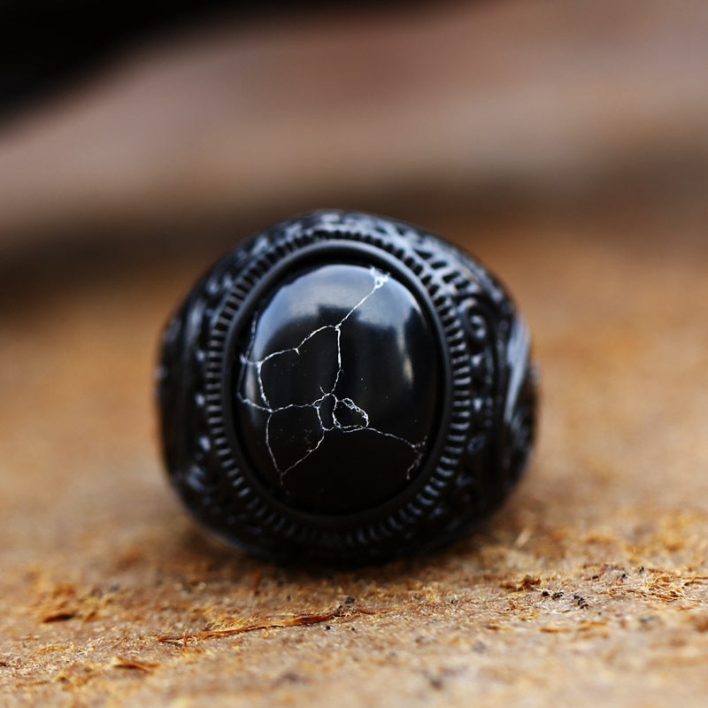Black stone ring with intricate design on a wooden surface