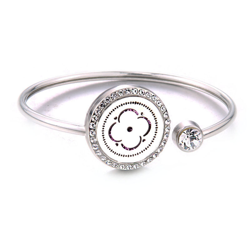 Silver bracelet with a circular charm featuring a flower design on a white background