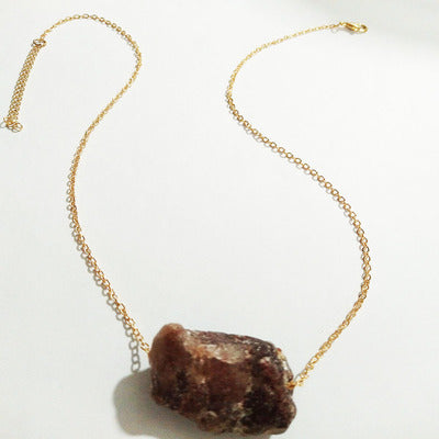Gold necklace with a brown stone pendant on a white background