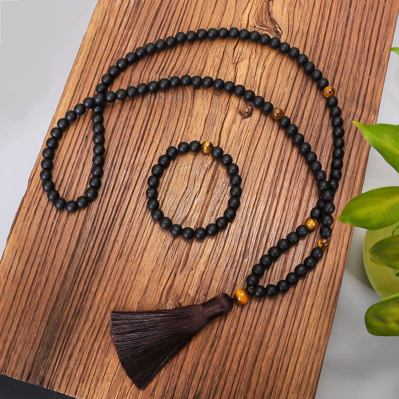 Black beaded necklace with a tassel on a wooden surface