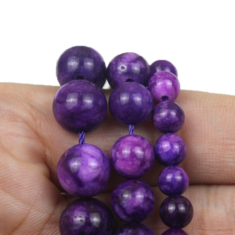 Purple beaded bracelet on a hand against a white background