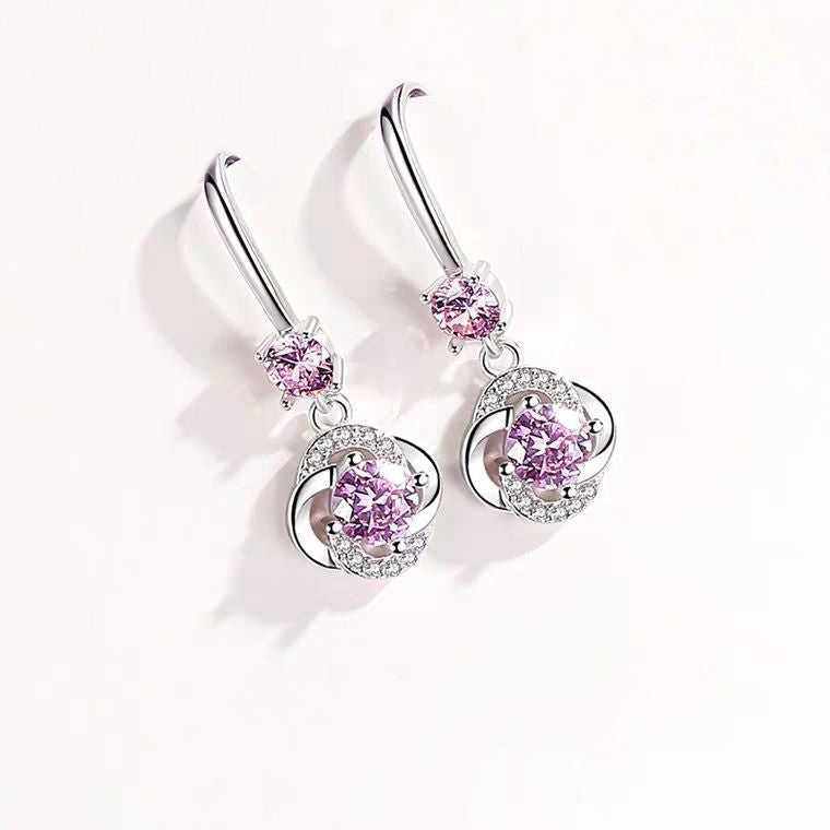 Pair of silver earrings with pink gemstones on a white background