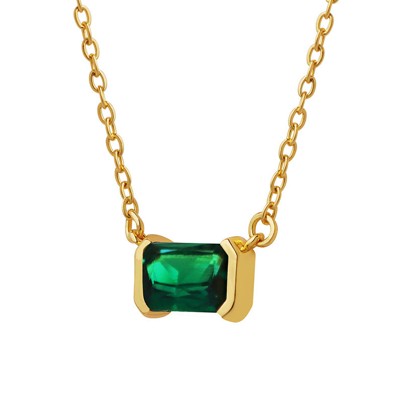 Gold necklace with a green gemstone pendant on a white background