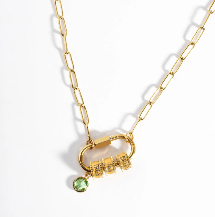 Gold necklace with a lock charm and green gemstone on a white background