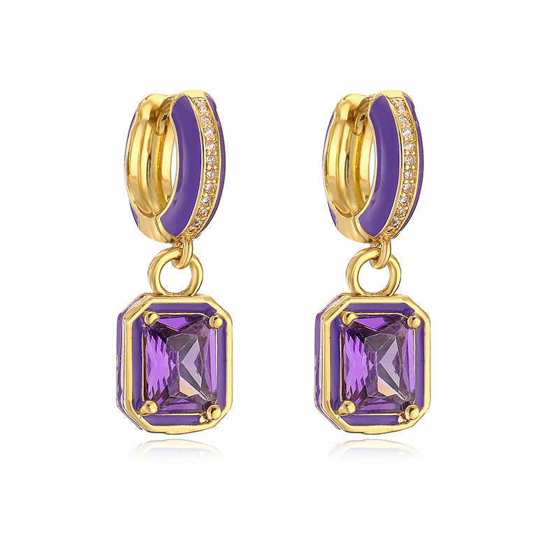 Gold hoop earrings with purple gemstones on a white background