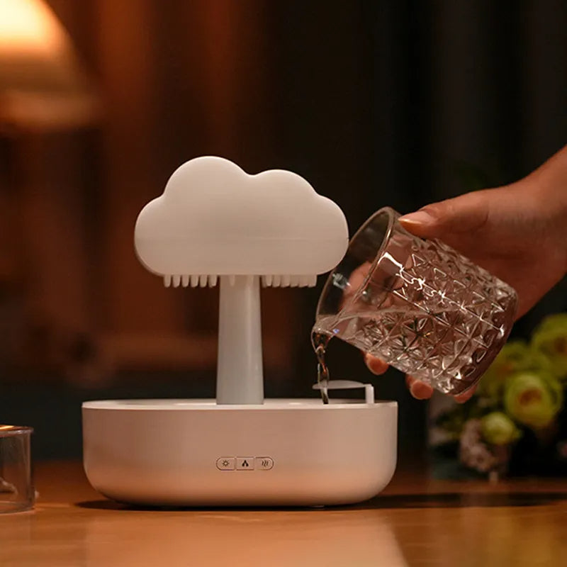 Cloud-shaped device on a table with a hand pouring water into it, blurred background