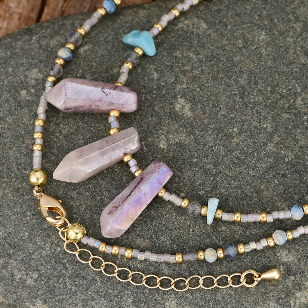 Necklace with crystal beads and gold chain on a stone surface