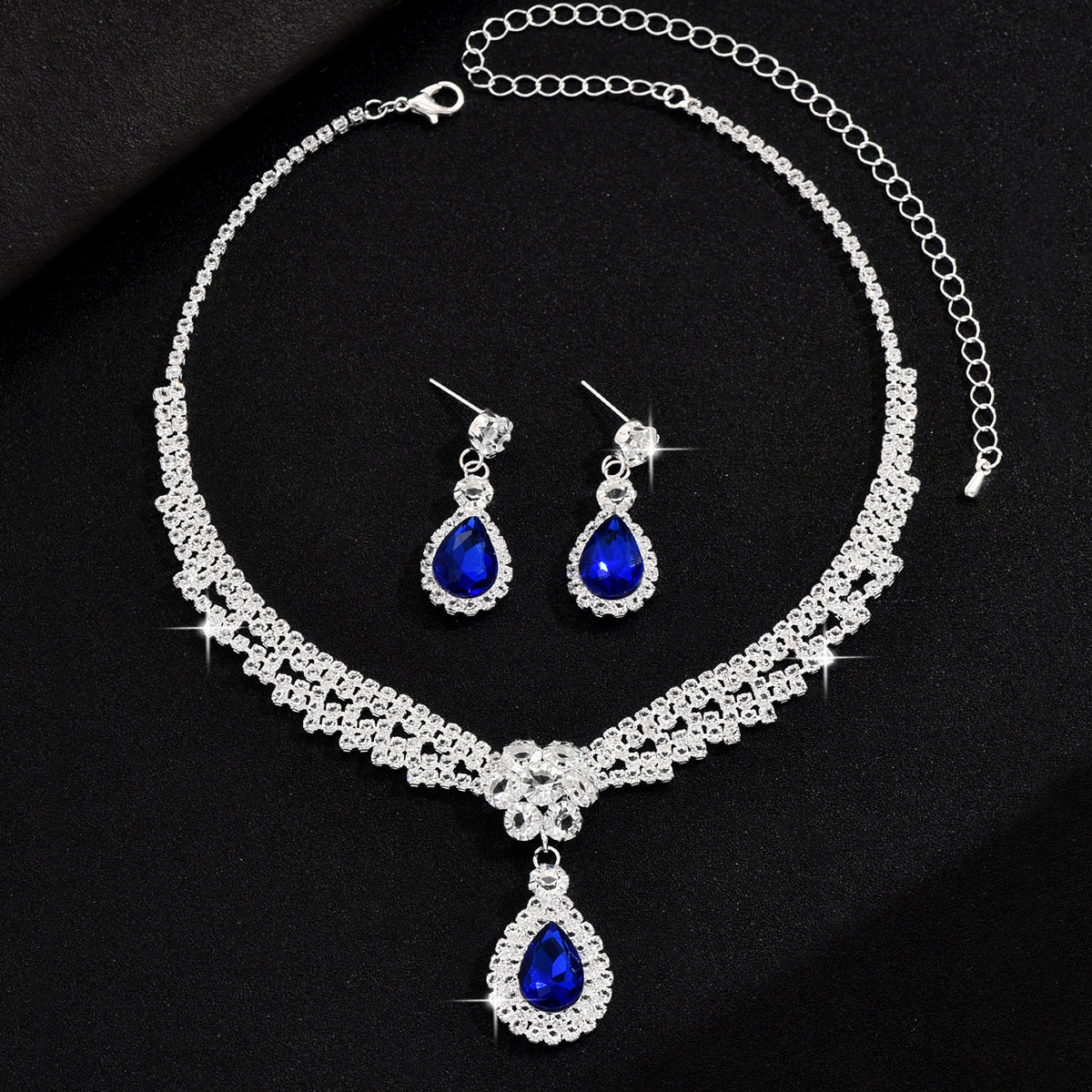 Jewelry set with necklace and earrings featuring blue teardrop stones on a black background