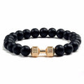 Black beaded bracelet with a gold dumbbell-shaped clasp on a white background