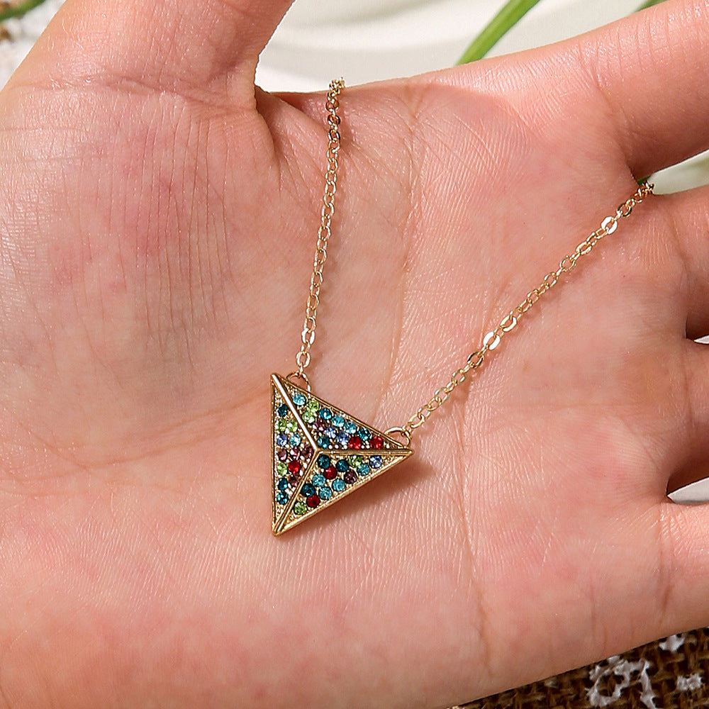 Gold necklace with a colorful triangle pendant held in a hand.