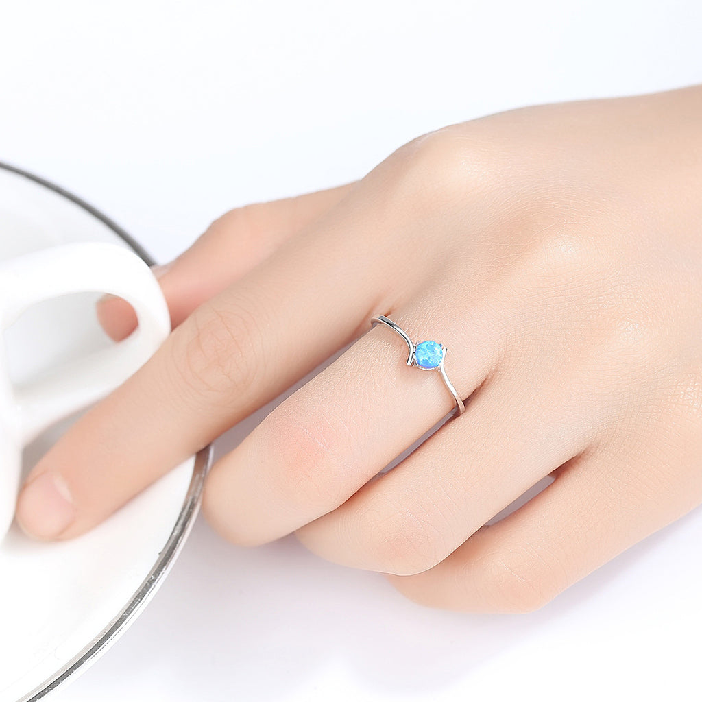 Hand wearing a ring with a blue gemstone on a white background