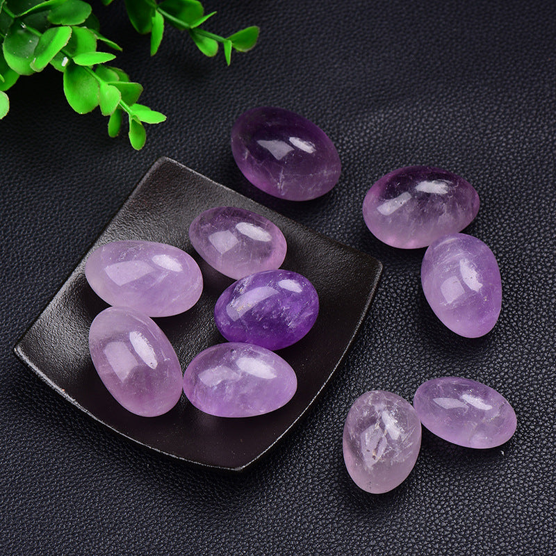 Purple stones on a black square plate with green leaves on a dark background