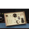 Set of tea-making tools in a box on a dark surface with a blue mat.