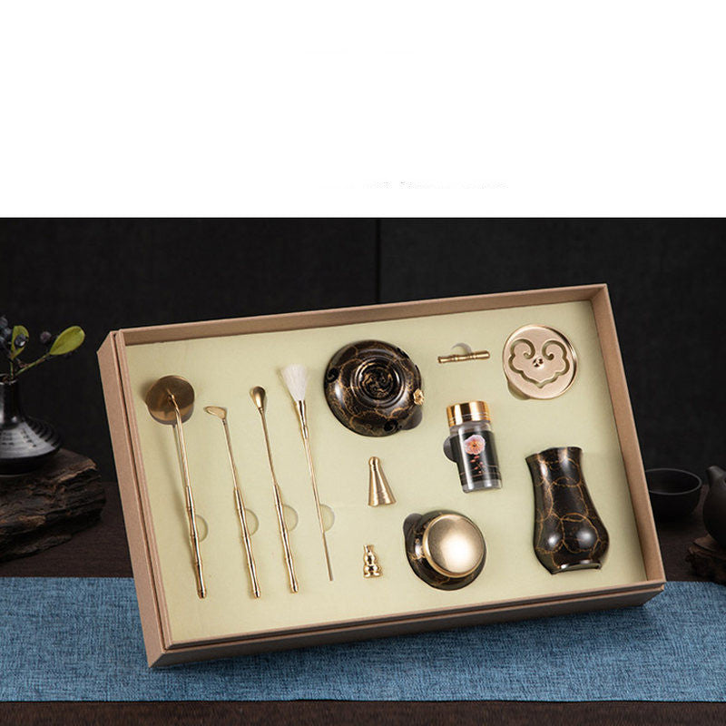 Set of tea-making tools in a box on a dark surface with a blue mat.