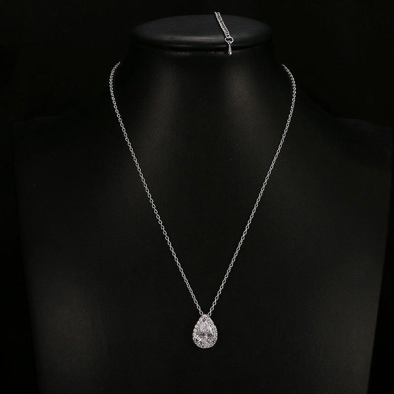 Silver necklace with a teardrop pendant on a black background