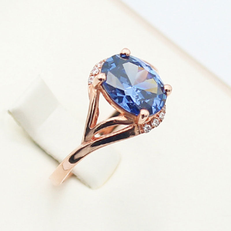 Rose gold ring with a blue gemstone on a light background