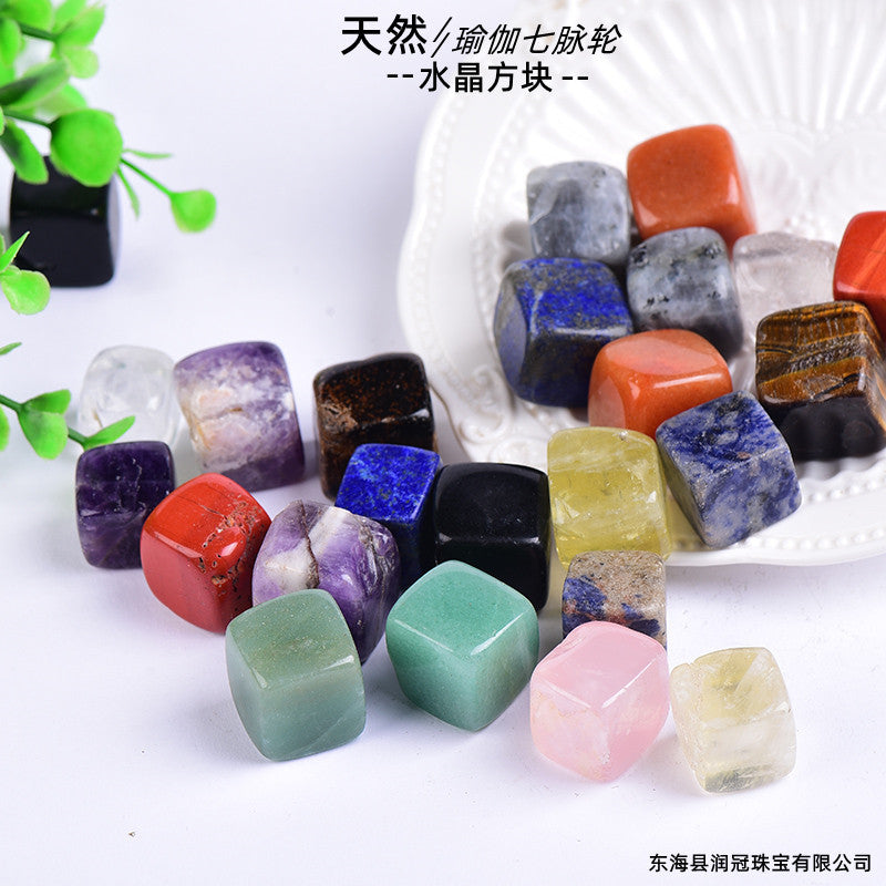 Assorted colorful crystals on a white surface with green leaves in the background