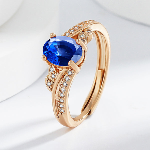Rose gold ring with a blue gemstone and small diamonds on a light gray background