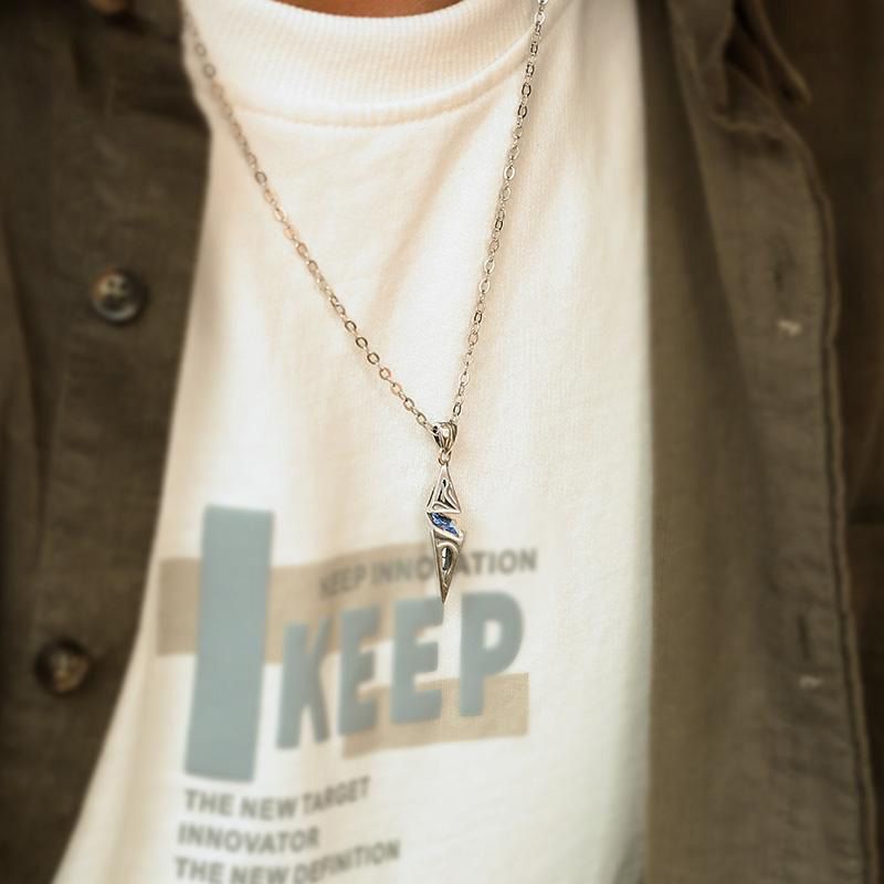 Necklace with a pendant on a person wearing a white shirt with text.