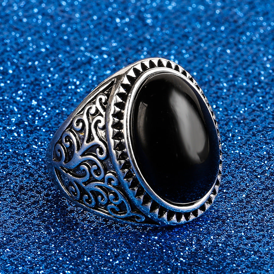 Silver ring with black stone on a blue glittery background