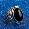 Silver ring with black stone on a blue glittery background