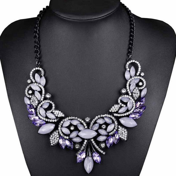 Decorative necklace with purple and white stones on a black mannequin.